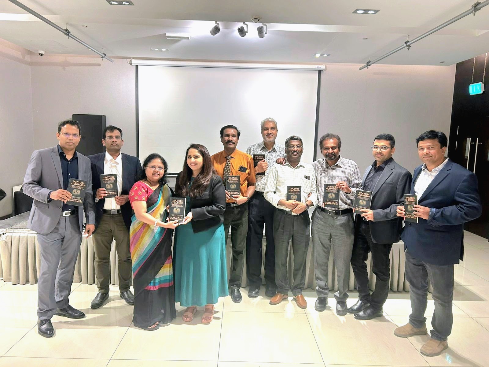 Group photo at the launch of Doctors at Jeopardy, attendees holding copies of the book